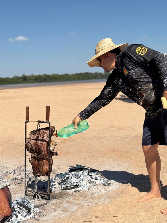 Regando o assado no fogo de chão — acampamento Toca do Jacaré, Rio Araguaia