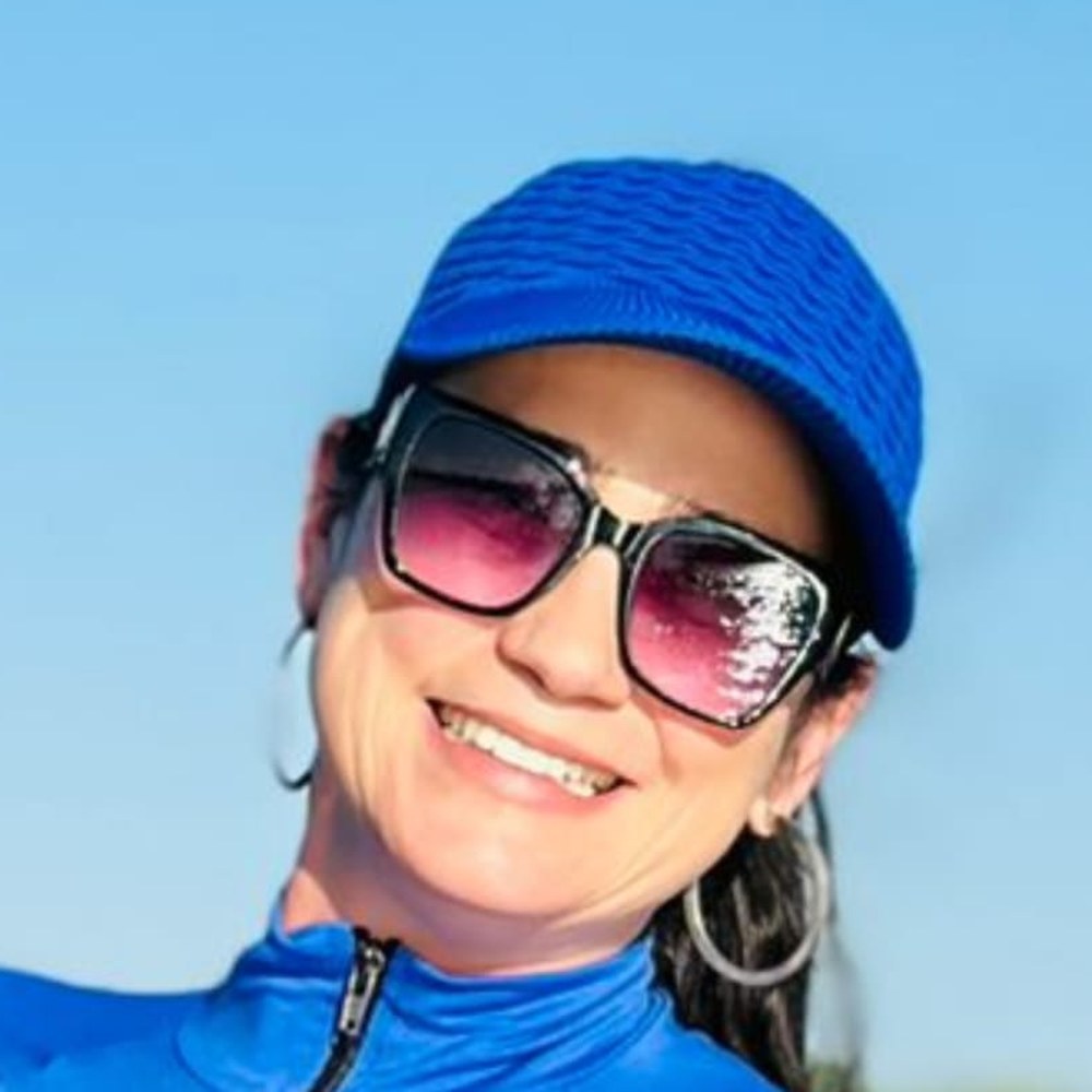 Sally Carla, Primeira Dama da Toca do Jacaré, sorrindo com boné azul em dia de sol no rio